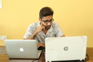 man looking at two computers - Front End Metrics