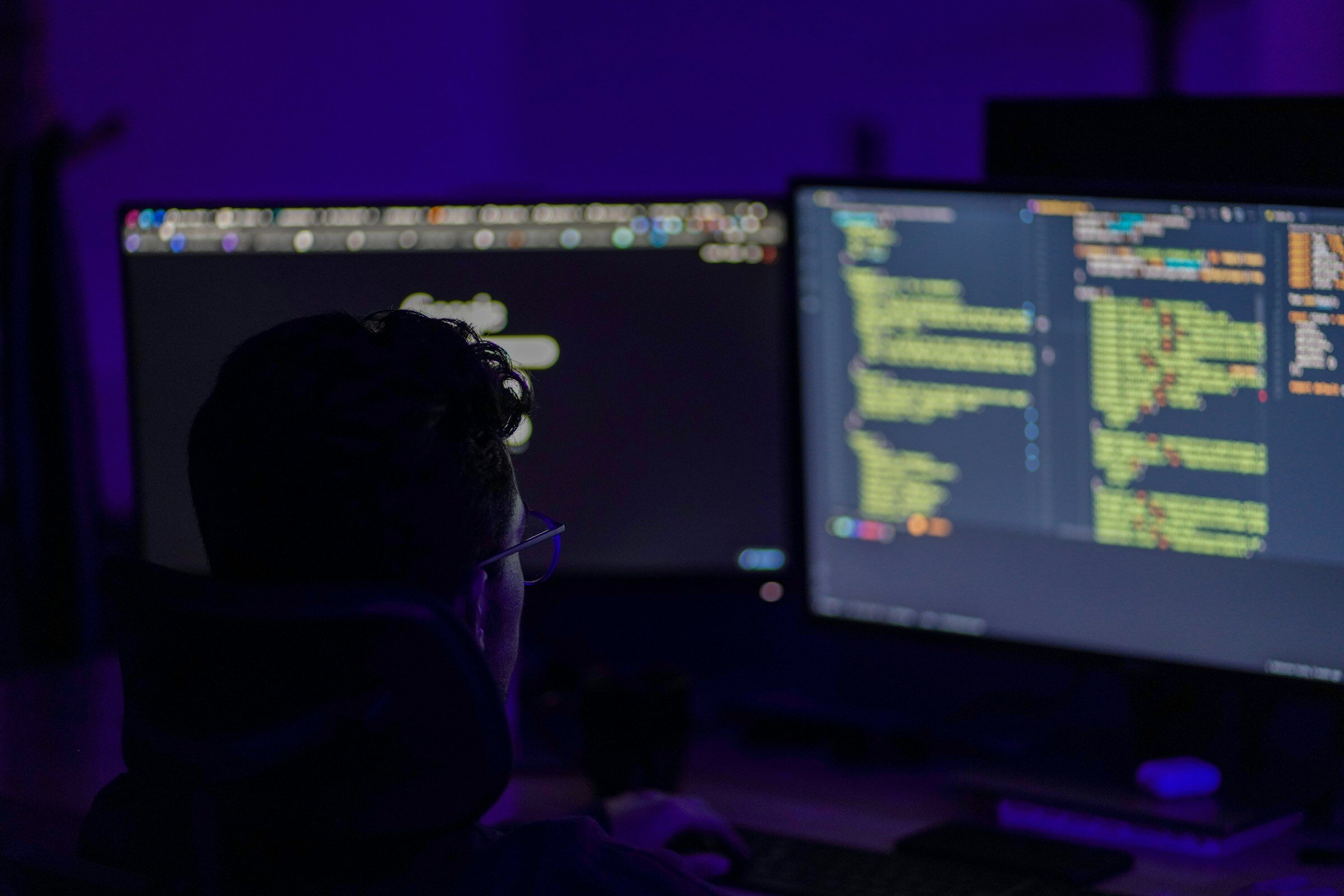 man sitting infront of coding computer - Log Monitoring Tools